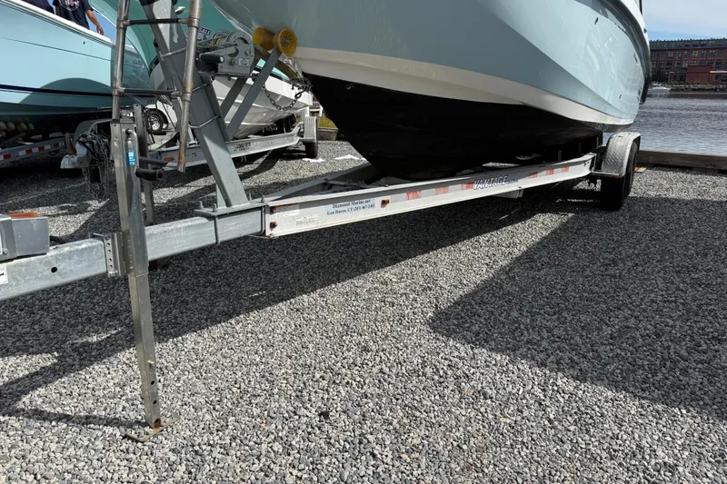 Slide: The Image of 2015 Boston Whaler 230 Vantage boat on trailer, parked on gravel near water. - 22