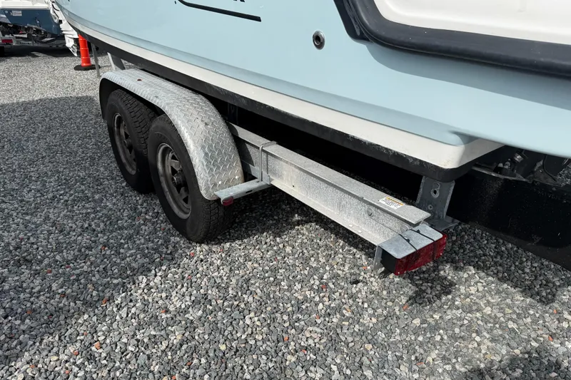 Slide: The Image of 2015 Boston Whaler 230 Vantage on a dual-axle trailer, parked on gravel. - 23
