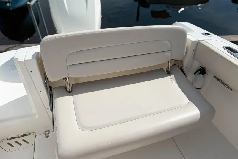 Slide: The Image of 2015 Boston Whaler 230 Vantage boat seat, white upholstery, docked by the water. - 5