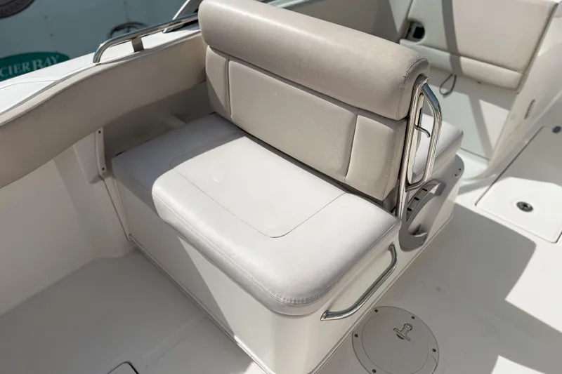Slide: The Image of 2015 Boston Whaler 230 Vantage boat seat with white upholstery and stainless steel accents. - 6