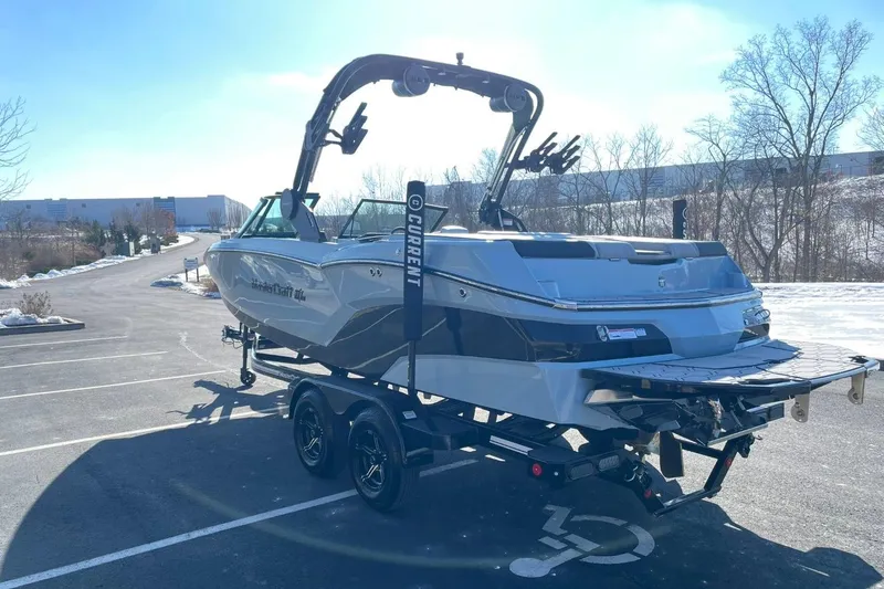 Slide: The Image of 2025 MasterCraft NXT22 boat on trailer in sunny parking lot. - 5