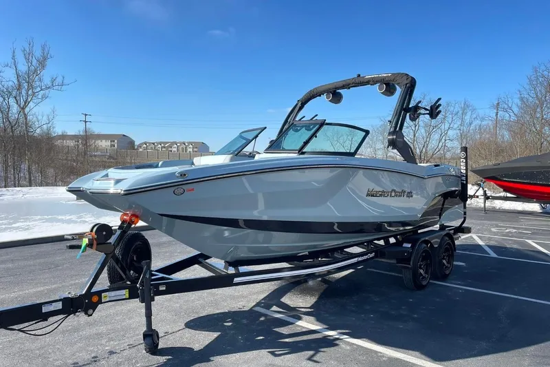 Slide: The Image of 2025 MasterCraft NXT22 boat on trailer in sunny parking lot. - 7