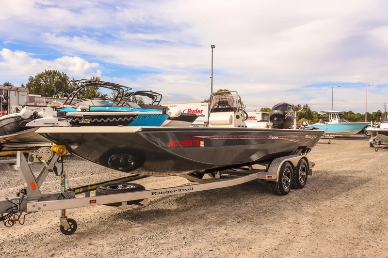 Slide: The Image of 2022 Ranger RB200 boat on trailer in outdoor lot under cloudy sky. - 2