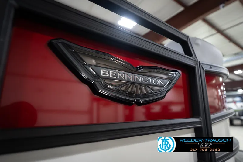 Slide: The Image of 2026 Bennington 22 ML boat emblem with red and black detailing in showroom. - 54