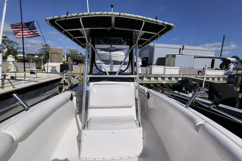 Slide: The Image of 2003 Century 2600 Center Console boat docked, featuring a T-top and seating, with an American flag. - 13