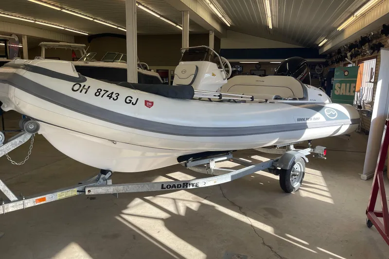 Slide: The Image of 2022 Walker Bay Venture 16 boat on trailer in showroom, featuring sleek design and modern features. - 1