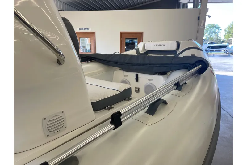 Slide: The Image of 2022 Walker Bay Venture 16 boat interior with seating and railing in a showroom. - 3