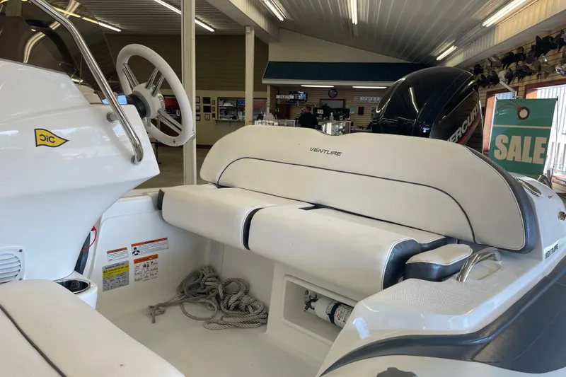 Slide: The Image of 2022 Walker Bay Venture 16 boat interior with seating and steering wheel in showroom. - 6