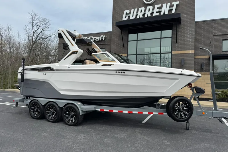 Slide: The Image of 2025 MasterCraft XStar 23 boat on trailer, parked outside a modern building. - 1