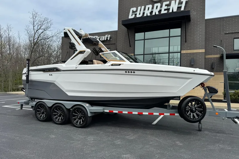Slide: The Image of 2025 MasterCraft XStar 23 boat on trailer outside showroom. - 2