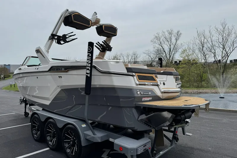 Slide: The Image of 2025 MasterCraft XStar 23 boat on trailer, parked near a pond with fountain. - 6