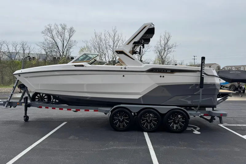 Slide: The Image of 2025 MasterCraft XStar 23 boat on trailer in parking lot. - 7