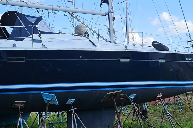 The Image of 2003 Beneteau Oceanis Clipper 393 sailboat on stands, blue hull, clear sky background. - 0