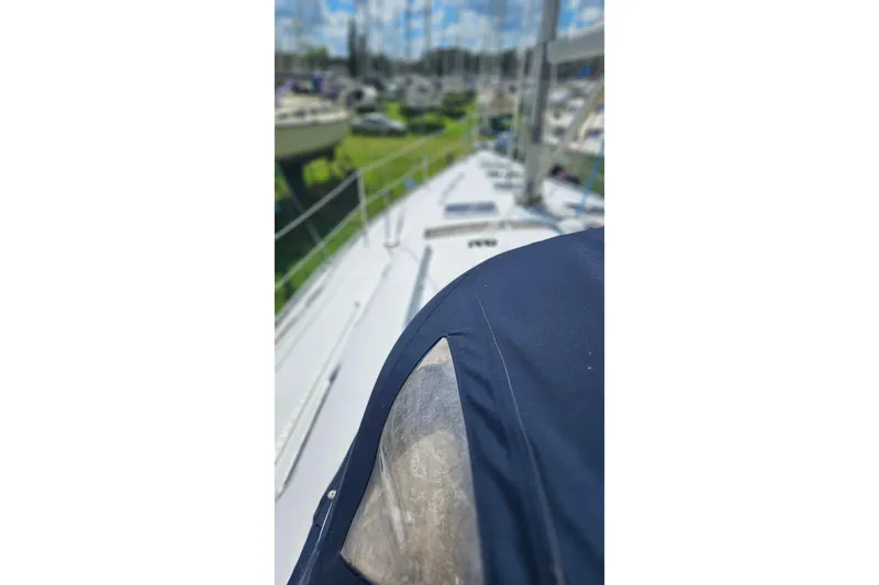 Slide: The Image of 2003 Beneteau Oceanis Clipper 393 sailboat deck with blue cover, marina background. - 11