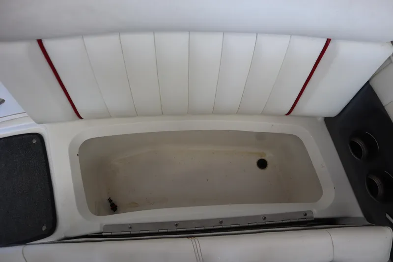 Slide: The Image of 2006 Cobalt 220 boat interior storage compartment with white upholstery and cup holders. - 17