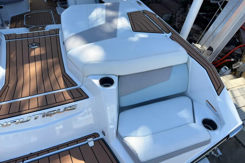 Slide: The Image of 2022 Nautique Super Air Nautique G23 Coastal Edition boat interior with cushioned seating and wood accents. - 19