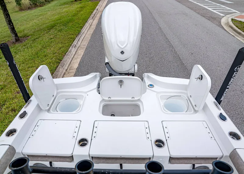 Slide: The Image of 2026 Sea Hunt BX 25 FS boat deck with storage compartments and motor, parked on roadside. - 11