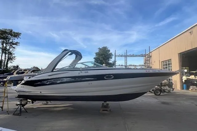 The Image of 2007 Crownline 320 LS boat parked outdoors near a warehouse. - 0