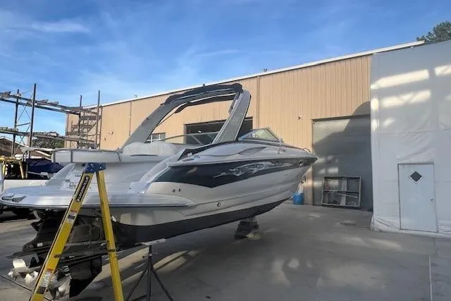 Slide: The Image of 2007 Crownline 320 LS boat on dry dock outside a warehouse under clear blue sky. - 2