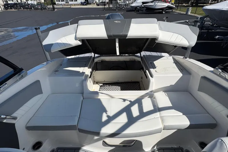 Slide: The Image of 2023 Chaparral 21 SSi OB boat interior with open storage compartment and cushioned seating. - 14