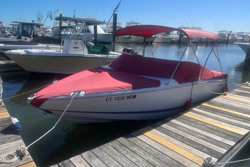 The Image of 2011 Cobalt 210 boat docked with red cover and canopy in a marina. - 0