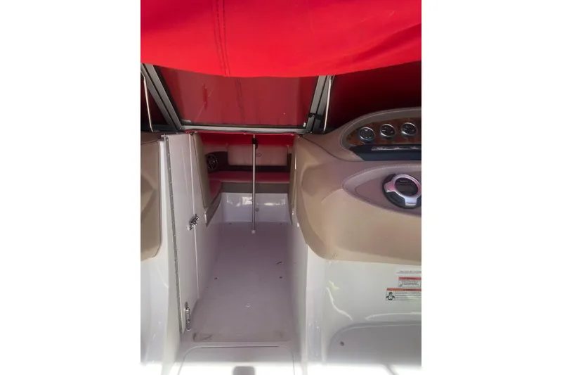 Slide: The Image of Interior view of a 2011 Cobalt 210 boat with red canopy and beige dashboard. - 11