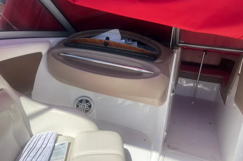 Slide: The Image of Interior of a 2011 Cobalt 210 boat with red canopy and beige seating. - 8