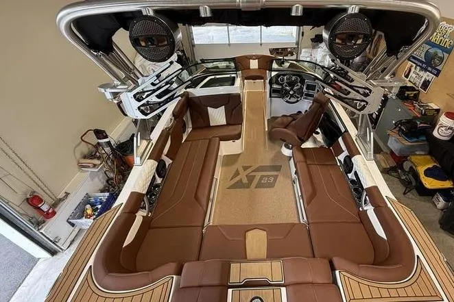 Slide: The Image of 2023 MasterCraft XT23 boat interior with brown seating and advanced audio system. - 5