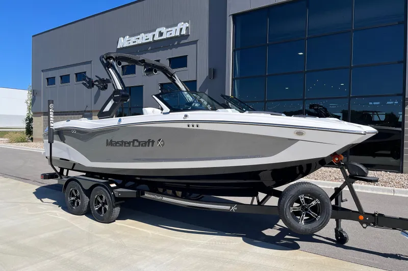 The Image of 2025 MasterCraft X22 boat on trailer outside showroom, sleek design, modern features. - 1