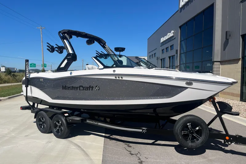 Slide: The Image of 2025 MasterCraft X22 boat on trailer outside dealership, sunny day. - 16