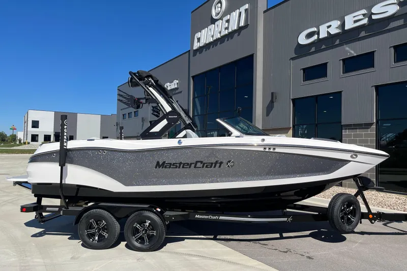 Slide: The Image of 2025 MasterCraft X22 boat on trailer outside dealership, showcasing sleek design and modern features. - 17