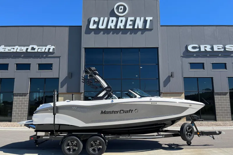 Slide: The Image of 2025 MasterCraft X22 boat on trailer outside dealership, showcasing sleek design. - 2