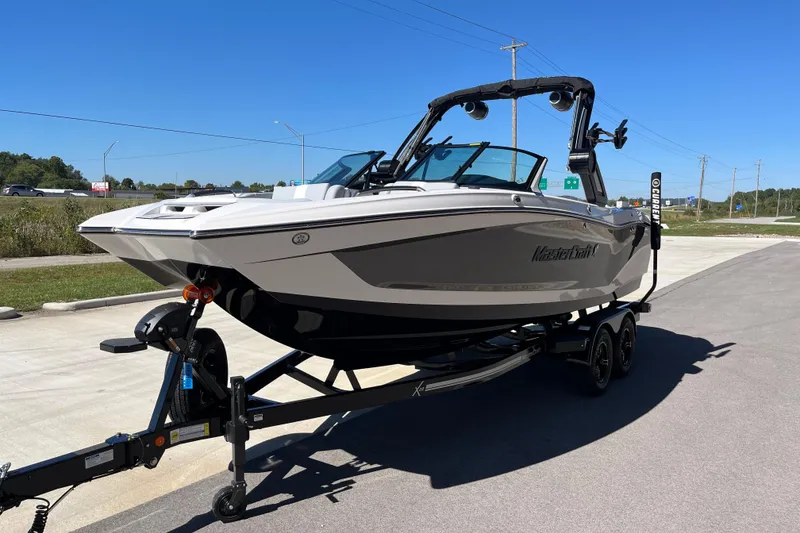 Slide: The Image of 2025 MasterCraft X22 boat on trailer, parked outdoors under clear blue sky. - 5