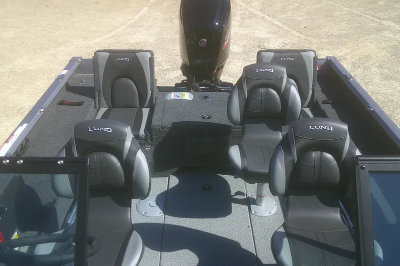 Slide: The Image of 2026 Lund 1775 Impact XS Sport boat interior with four black seats and motor. - 11