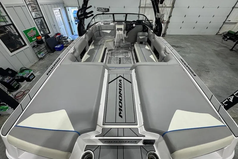 Slide: The Image of 2020 Moomba Makai boat interior with gray seating and sleek design in a garage setting. - 9
