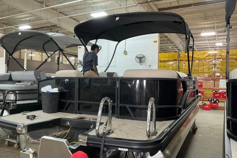 Slide: The Image of 2026 Bennington 22 SSRSE pontoon boat in a factory setting with a worker onboard. - 8