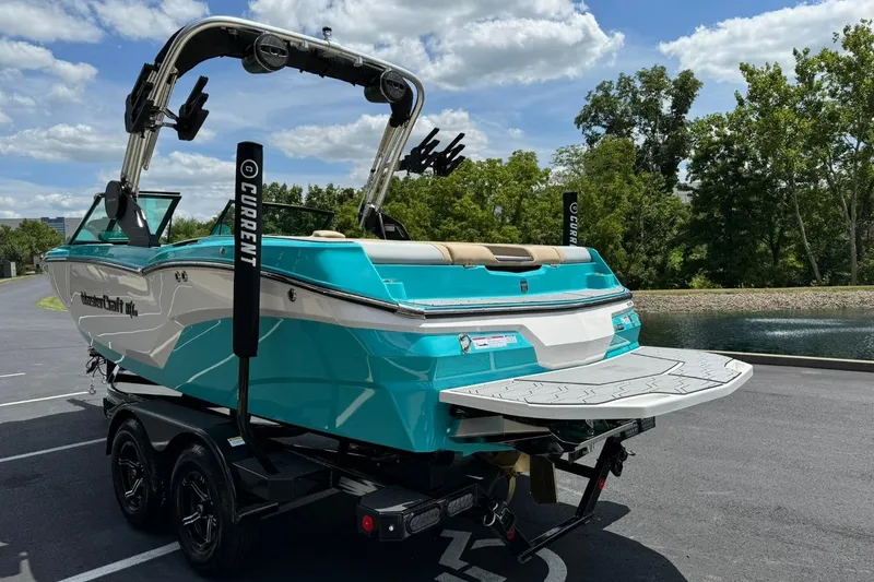 Slide: The Image of 2025 MasterCraft NXT20 boat on trailer, turquoise and white, parked near water. - 5