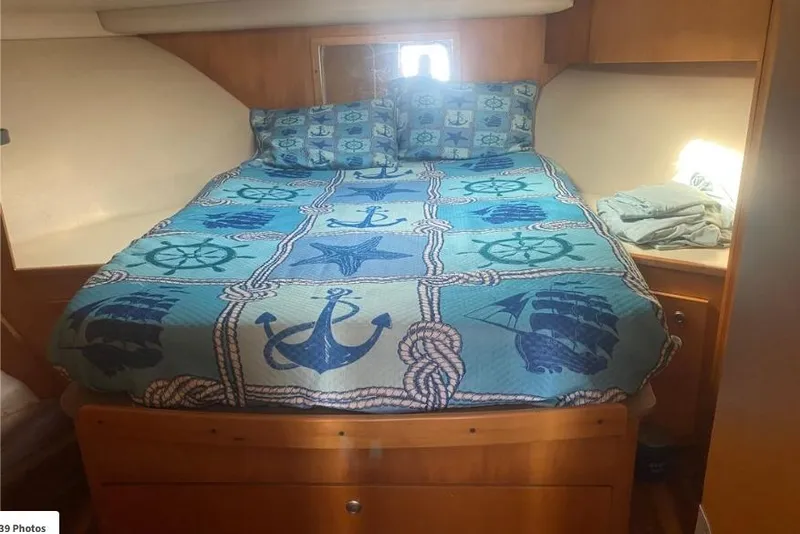 Slide: The Image of Cozy cabin interior of 2000 Luhrs Tournament 360 Convertible with nautical-themed bedding. - 10