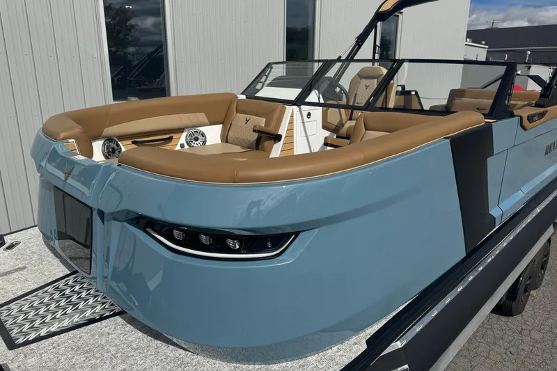 Slide: The Image of 2026 Revel RS25 boat with sleek design, blue exterior, and tan seating, docked outdoors. - 9