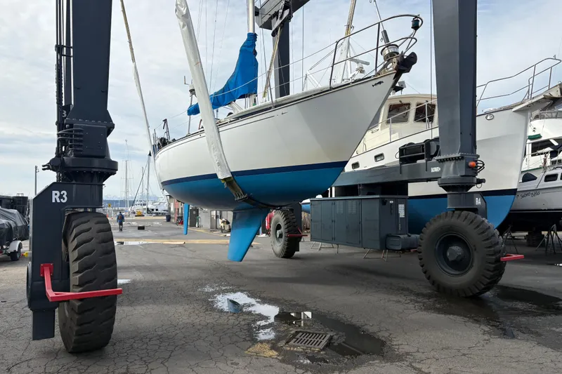 Slide: The Image of 1980 C&C 36 sailboat lifted by a boat hoist in a marina. - 28