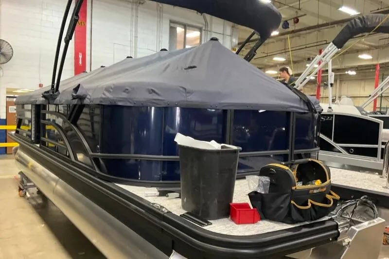 Slide: The Image of 2026 Bennington 23 SSRSF pontoon boat in a workshop, covered and equipped with tools. - 13