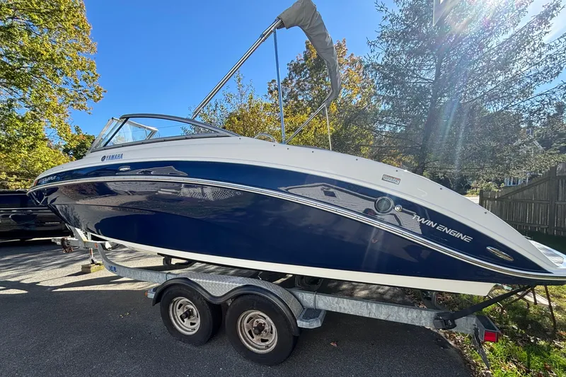 The Image of 2012 Yamaha AR240 HO boat on trailer, blue and white, parked outdoors. - 0