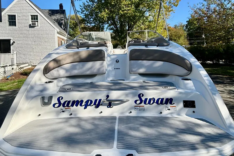Slide: The Image of 2012 Yamaha Boats AR240 HO named "Sampy's Swan" with cushioned seating, docked outdoors. - 2