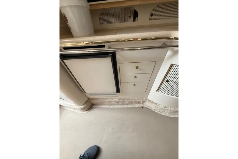 Slide: The Image of Interior of 2000 Sea Ray 310 Sundancer showing kitchenette with fridge and storage drawers. - 21