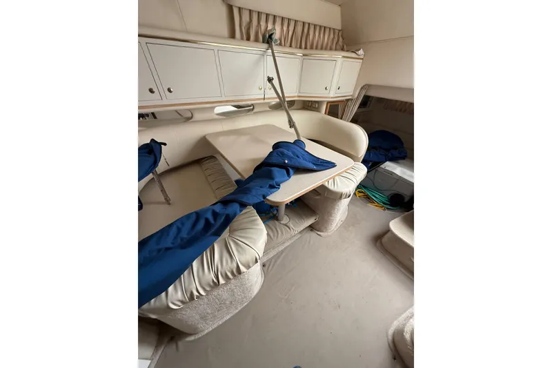 Slide: The Image of Interior of 2000 Sea Ray 310 Sundancer with seating and table, featuring blue covers. - 25