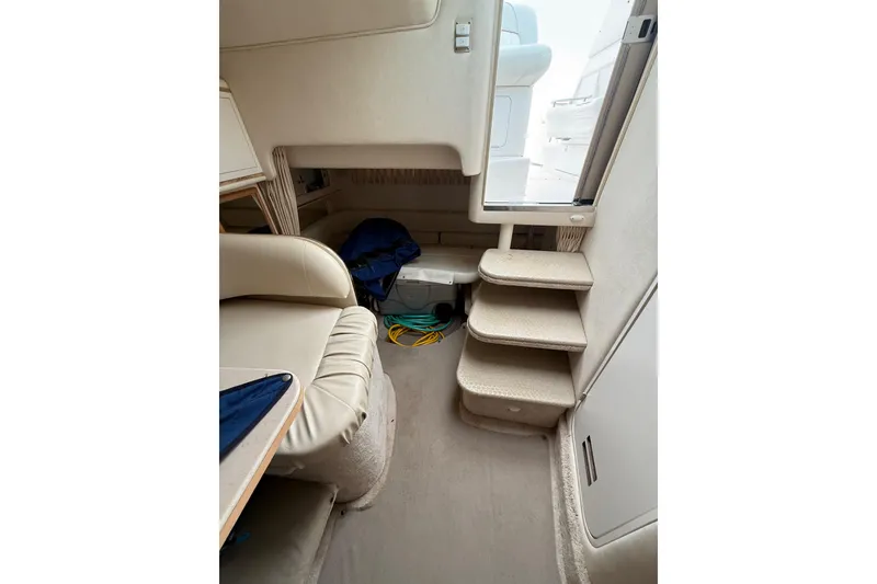 Slide: The Image of Interior of 2000 Sea Ray 310 Sundancer boat, featuring beige seating and compact stairs. - 28