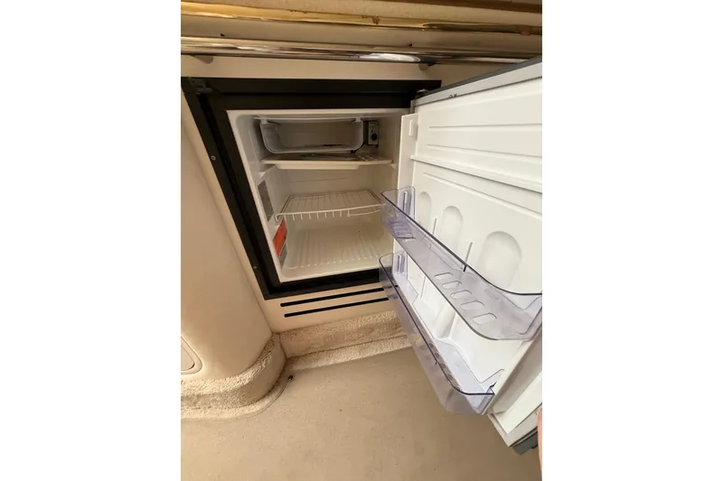 Slide: The Image of Open refrigerator inside 2000 Sea Ray 310 Sundancer boat, showing empty shelves and door compartments. - 29