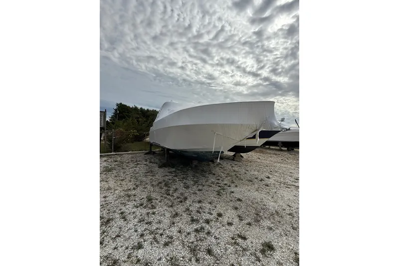 Slide: The Image of 2000 Sea Ray 310 Sundancer boat covered and stored outdoors under cloudy sky. - 39