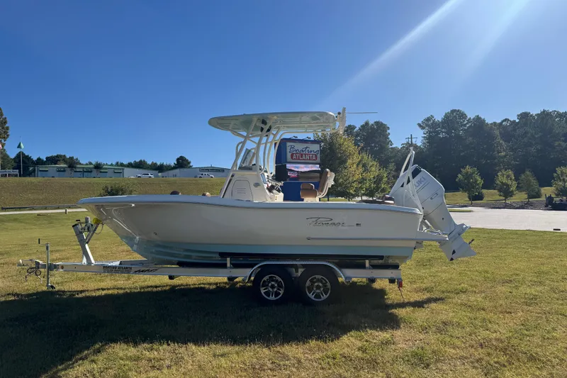 Slide: The Image of 2026 Pioneer 222 Islander boat on trailer, parked on grass under clear blue sky. - 1