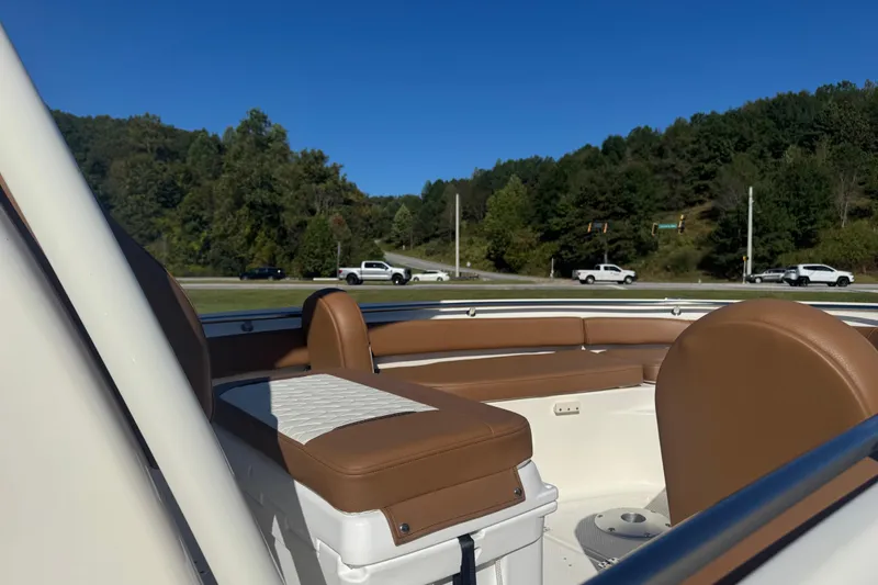 Slide: The Image of 2026 Pioneer 222 Islander boat interior with brown seating, parked near a road and trees. - 8